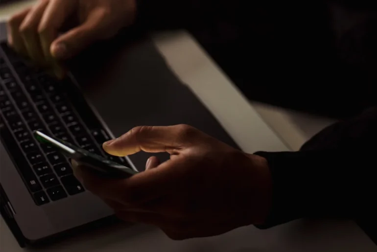 man holding phone with laptop